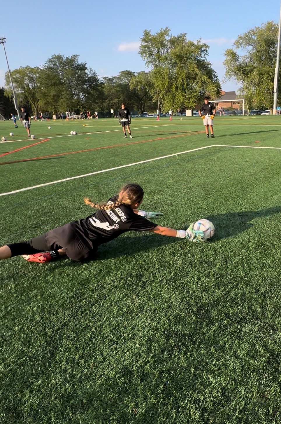 Goalkeeper stretching to stop a low shot on the training field
