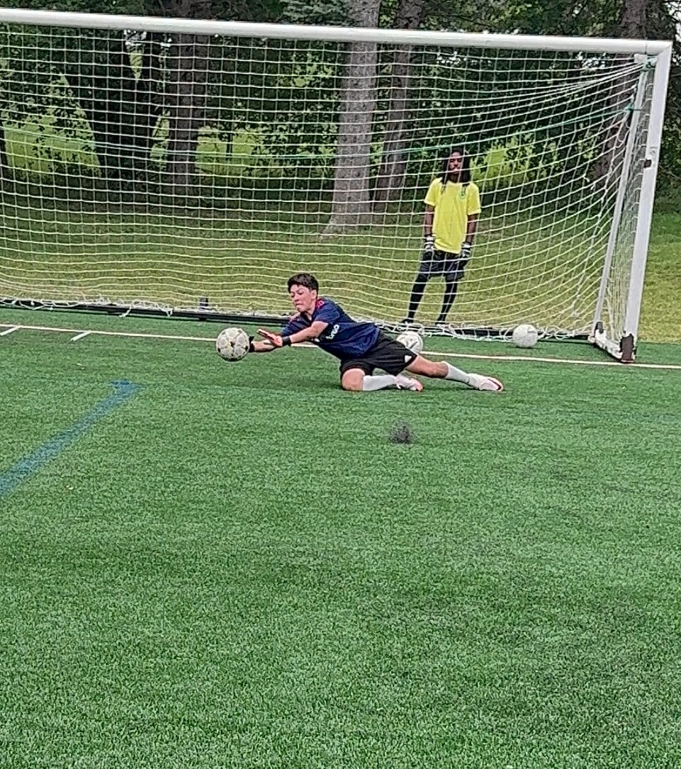 Young goalkeeper diving to make a low save during training