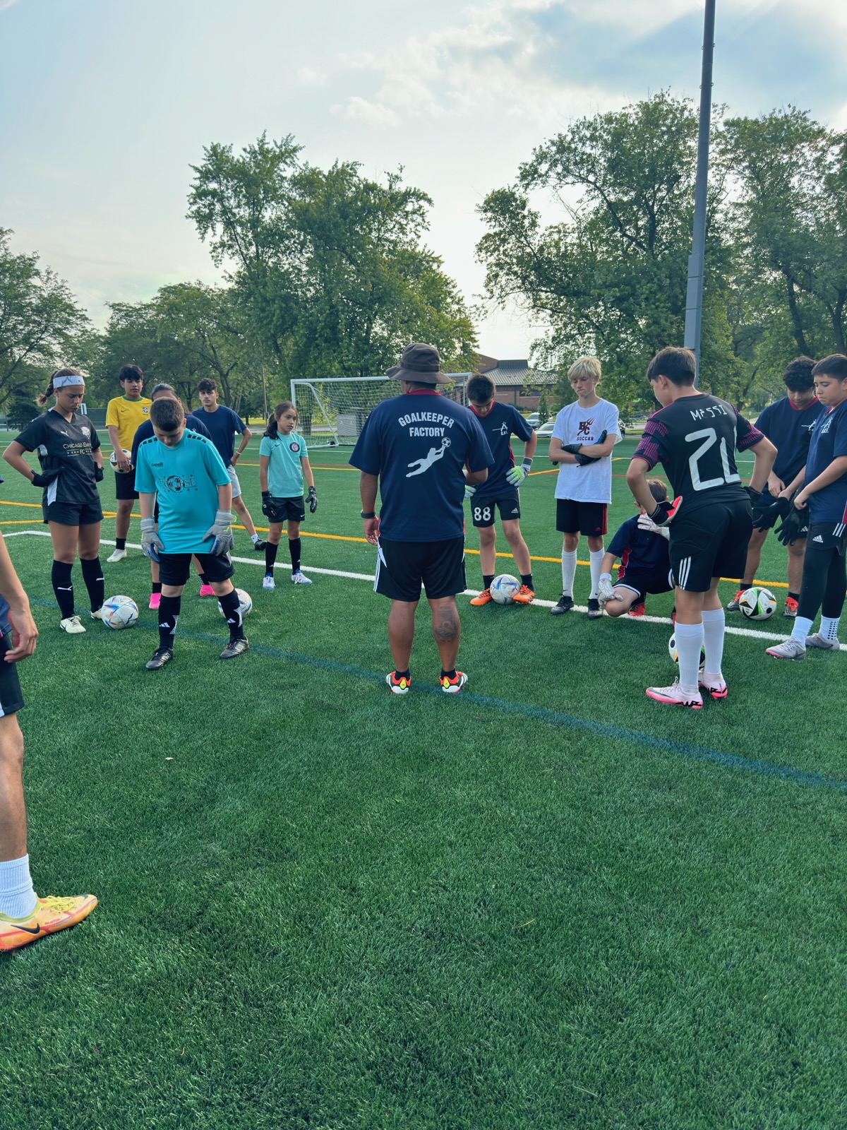 Young goalkeepers gathered around their coach during a WCOB training session
